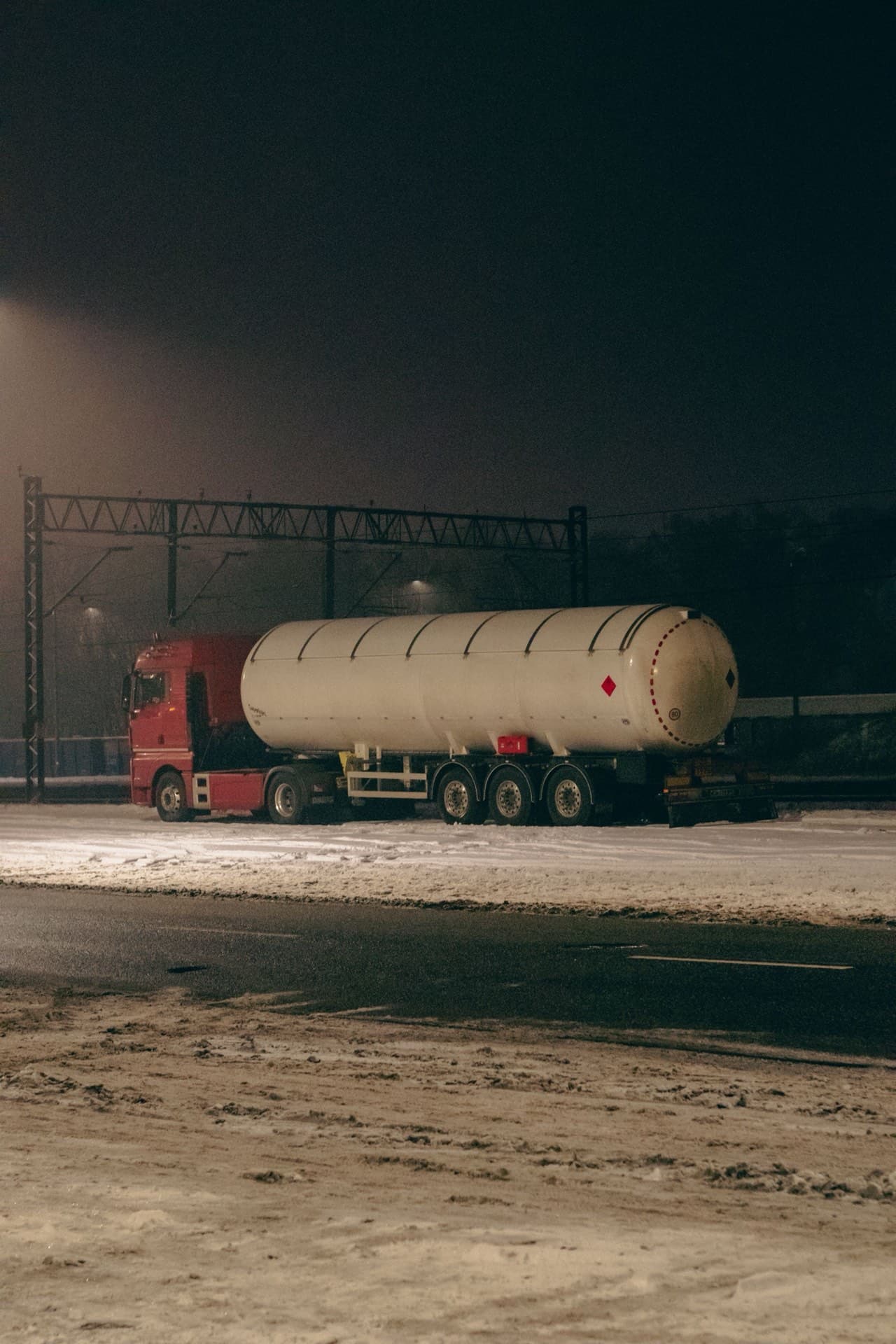 Red tanker truck under floodlights at a freight depot at night