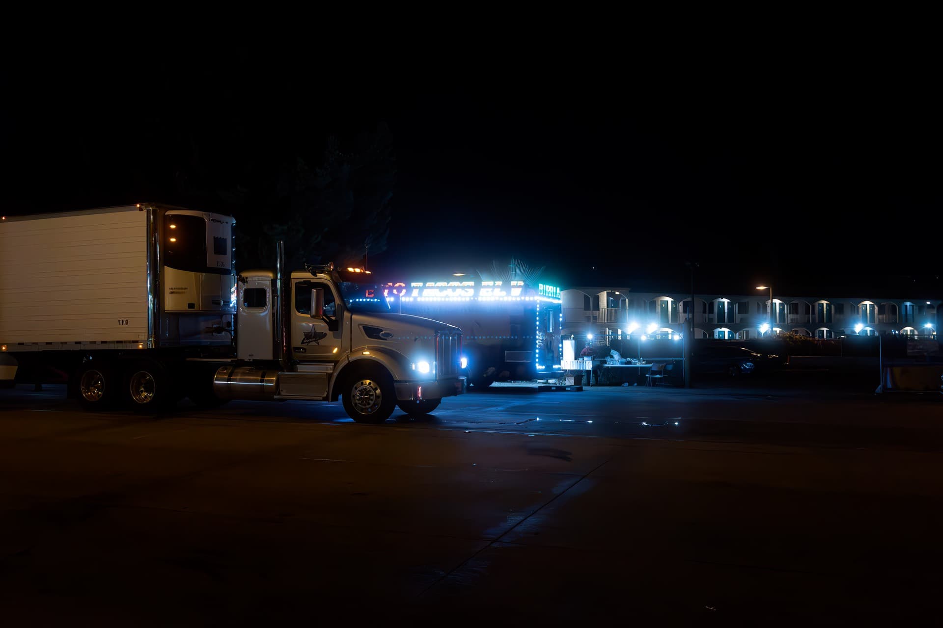 Trucks parked at an illuminated truck stop at night