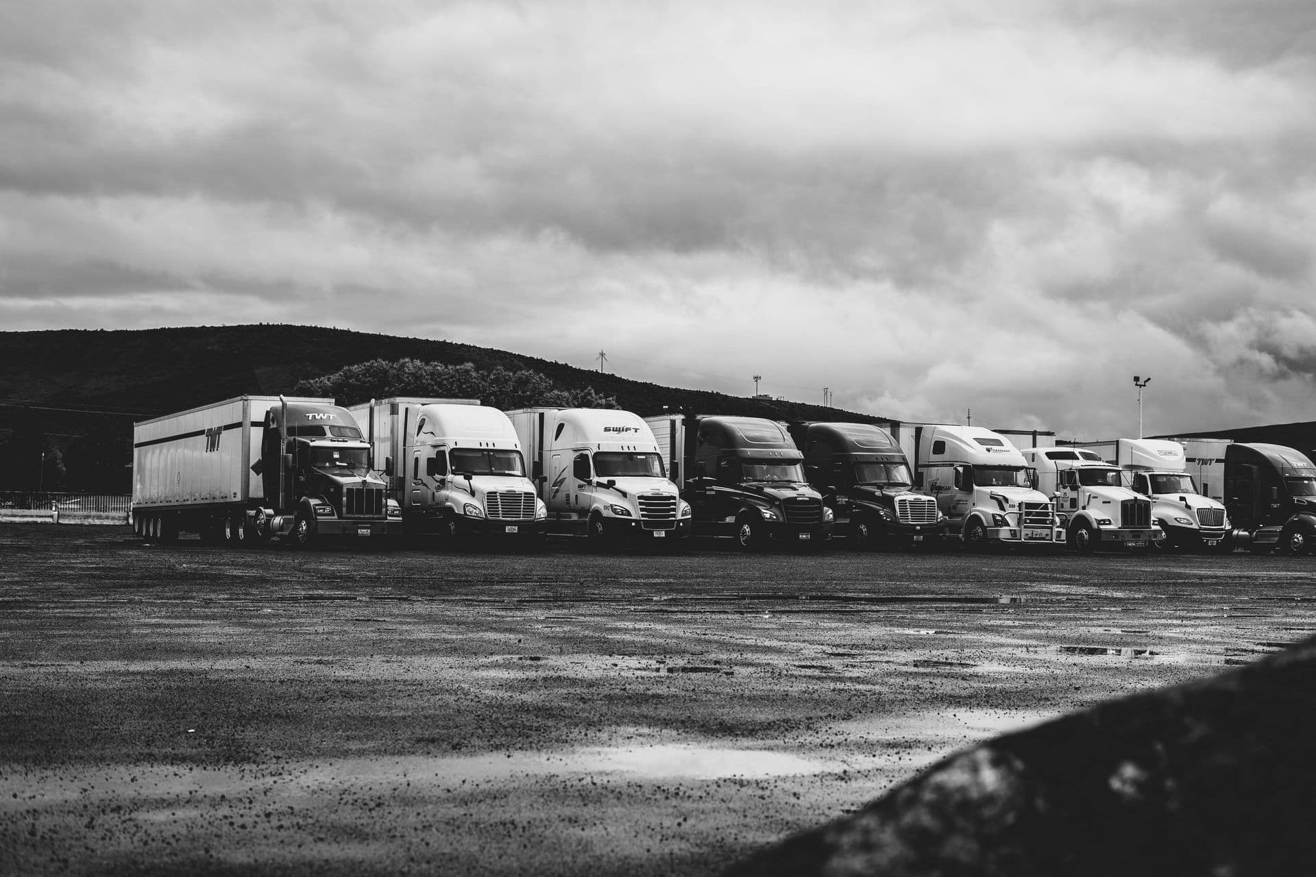 Row of parked semi trucks under a dramatic sky